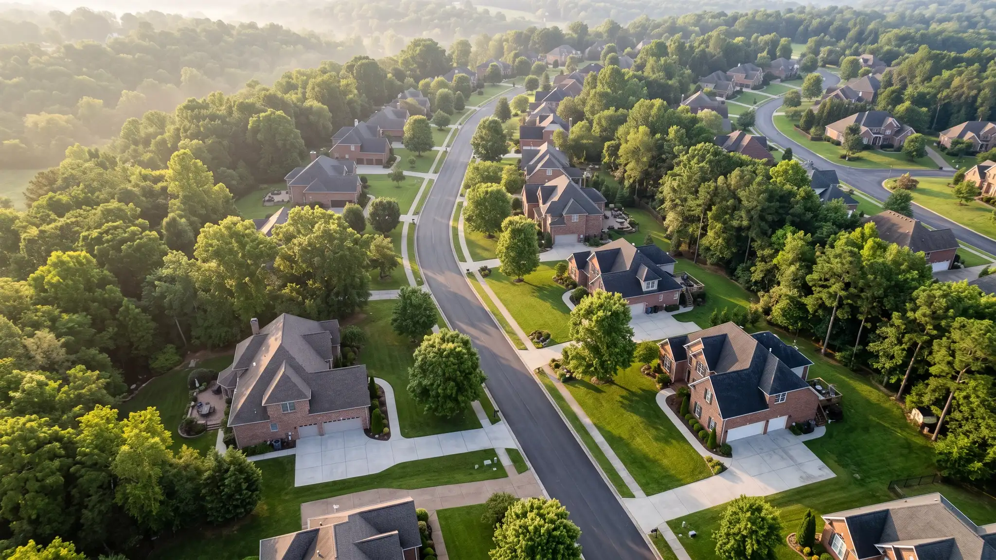 Concrete FAQ | Music City Concrete An aerial view of a Tennessee neighborhood with brick homes, mature trees and clean concrete driveways along winding streets in soft morning light